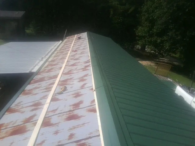 Old rusted panels beside newly installed green metal roofing — Wind Damage Roof Repair by Roofing Brothers in Malden On Hudson