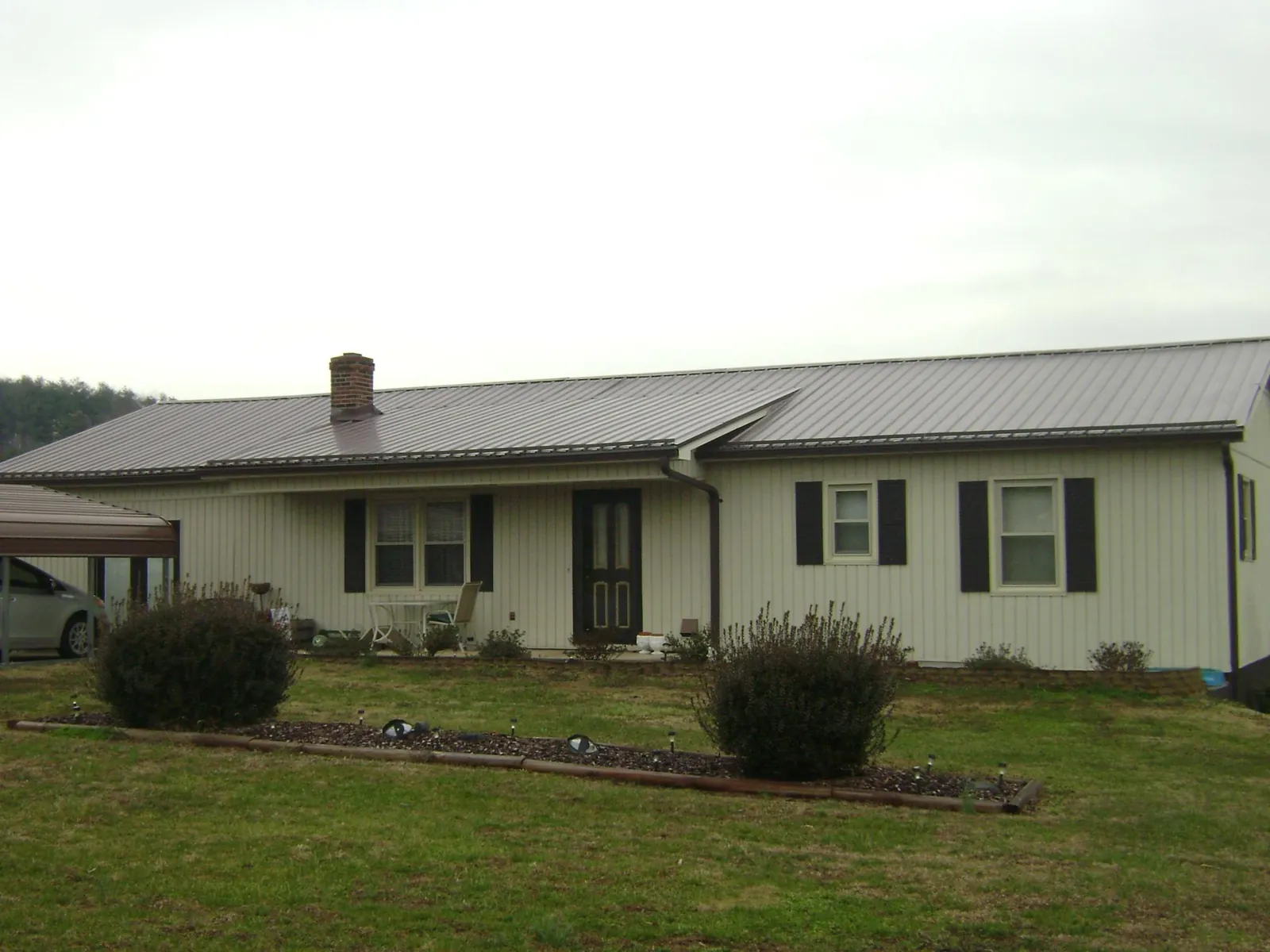 Brown metal roof on a cream sided ranch home with a brick chimney in Malden On Hudson