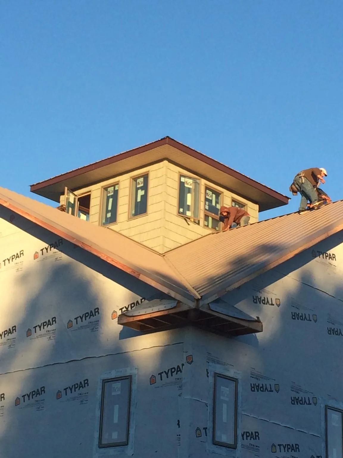 Roofers working around a rooftop cupola on a new metal roof at sunset — Roof Waterproofing in Malden On Hudson by Roofing Brothers